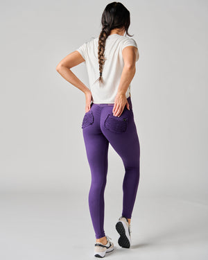 Person wearing purple leggings and a white top on a gray background