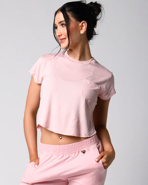 A person wearing a pink t-shirt with a front right pocket, paired with matching pink shorts.