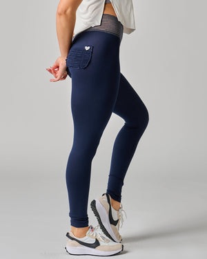 Person wearing navy leggings with a plain background