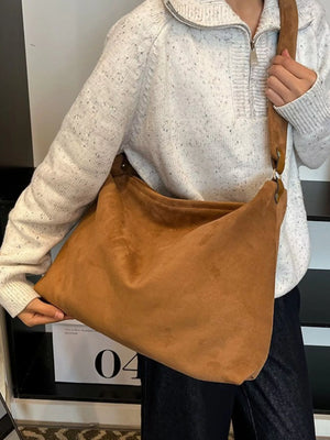 Person holding a brown leather bag with a neutral background