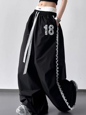 Black wide-leg pants with white drawstring and number '18' on a gray background