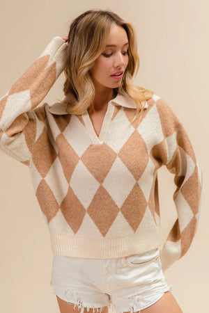 Woman wearing a beige and white argyle sweater with white shorts on a beige background
