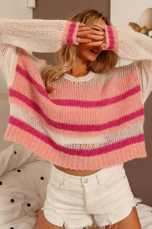 Person wearing a pink and white striped sweater with a blurred background