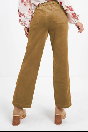 Brown corduroy pants worn with a floral blouse on a white background