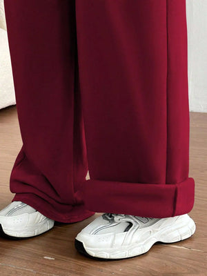 Maroon pants with white sneakers on a wooden floor