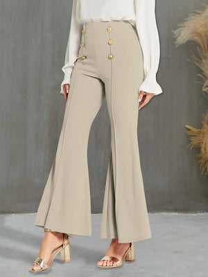 Beige flared pants with gold buttons worn by a person against a gray background