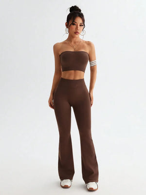 Woman wearing a brown strapless top and high-waisted pants on a white background