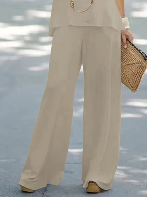 Person wearing beige pants holding a woven bag on a light blue background