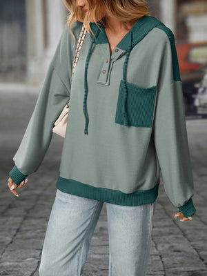 Person wearing a green and gray sweater with a blurred background