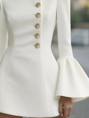 Close-up of a white dress with gold buttons and flared sleeves.