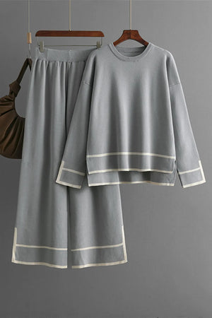 Gray sweater and skirt set on hangers against a gray background