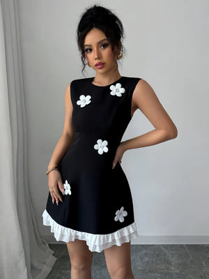 Woman wearing a black dress with white floral patterns against a neutral background