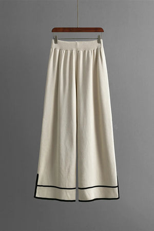 White wide-leg pants with black trim on a gray background