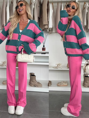 Woman wearing a pink and teal striped sweater with matching pants in a clothing store.