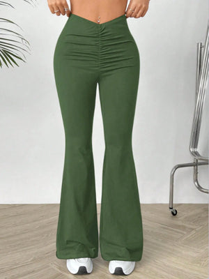 Green flared pants worn by a person on a plain background