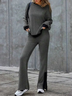 Person wearing a gray outfit with wide-leg pants against a concrete wall.