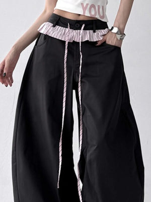 Person wearing black wide-leg pants with a ruffled waistband on a white background