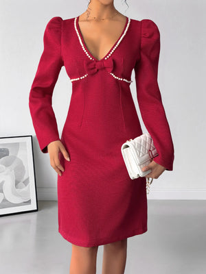 Red dress with puff sleeves and a white clutch on a plain background