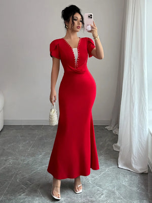 Woman in a red dress taking a mirror selfie in a room with gray flooring and white curtains.