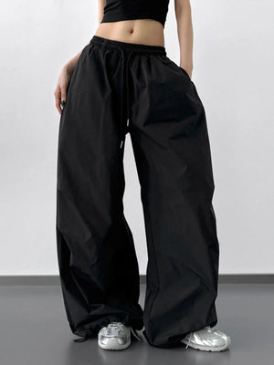 Person wearing black wide-leg pants and a black crop top on a plain background