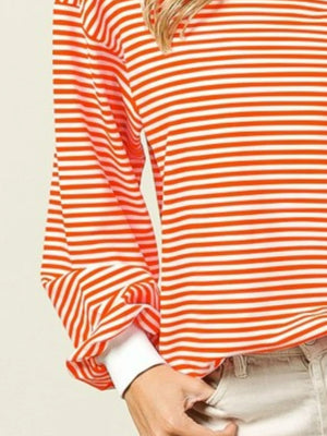 Orange and white striped shirt worn by a person on a beige background