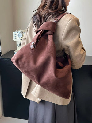 Person wearing a brown leather backpack in front of a sewing machine.