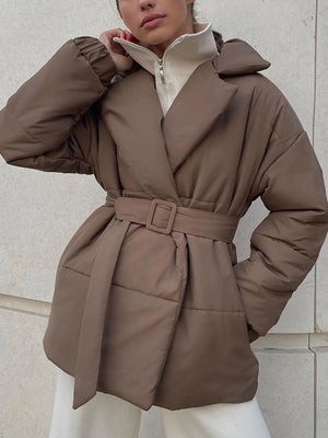 Brown puffer coat worn by a person against a light-colored wall.