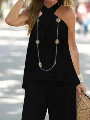 Person wearing a black sleeveless top with a long necklace, standing outdoors.