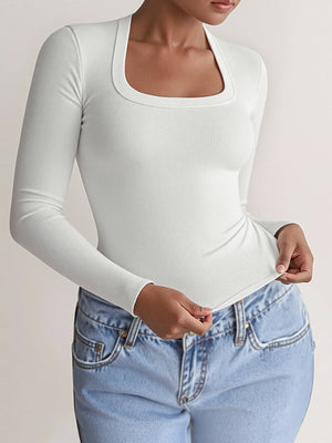 Person wearing a white long-sleeve top and light blue jeans on a plain background