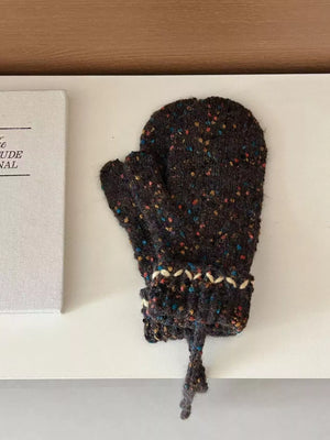 Dark brown knitted glove with speckled pattern on a white surface