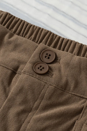 Close-up of brown corduroy pants with buttons on a white background