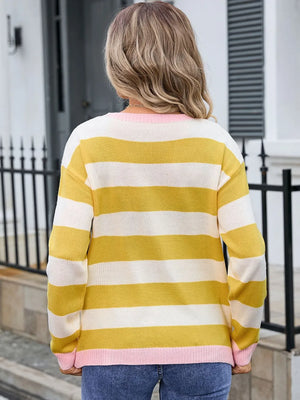 Person wearing a yellow and white striped sweater with pink trim outdoors.