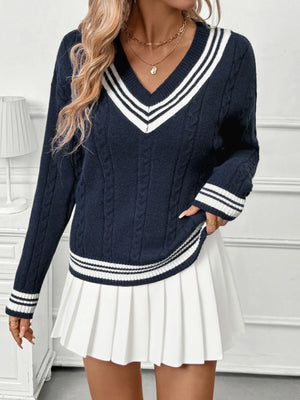 Person wearing a navy sweater with white stripes and a white pleated skirt.