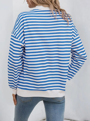 Person wearing a blue and white striped sweater with a plain background