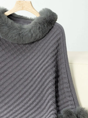 Gray knitted poncho with fur trim on a hanger against a white background