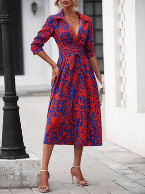 Woman wearing a red and blue patterned dress standing on a street.