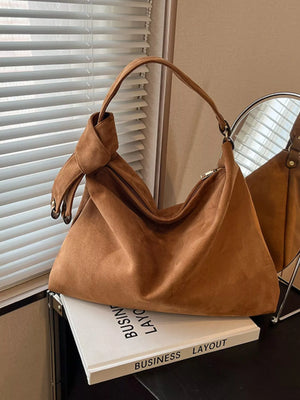 Brown handbag on a stack of books with a window and mirror in the background