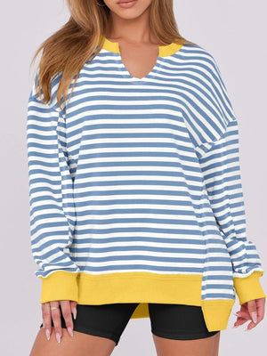 Blue and white striped long-sleeve top with yellow accents worn by a person on a plain background