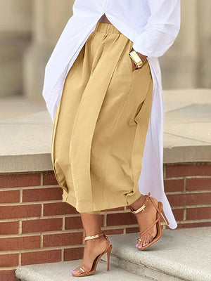 Person wearing beige pants and white shirt with gold shoes on a stone step.
