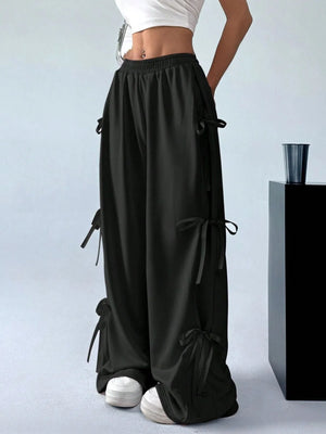 Black wide-leg pants with drawstrings worn by a person on a light gray background