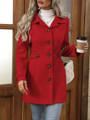 Person wearing a red coat holding a coffee cup in front of a wooden door.