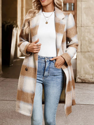 Woman wearing a plaid coat, white sweater, and blue jeans outdoors.