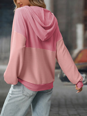Person wearing a pink hoodie with a blurred background