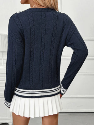 Navy blue cable knit sweater with white trim worn by a person on a white background