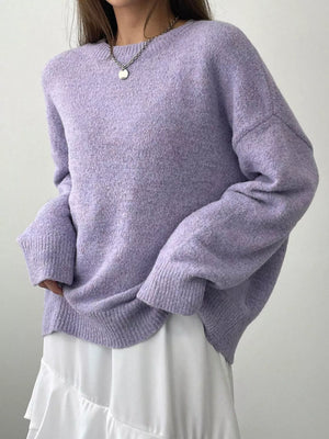 Person wearing a light purple sweater and white skirt against a plain background