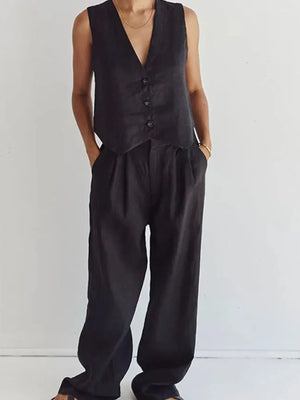 Person wearing a black vest and wide-leg pants against a white background