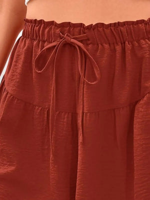 Close-up of a rust-colored skirt with a tie waist.