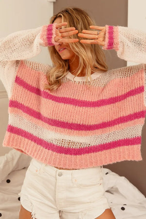 Person wearing a pink and white striped sweater with a blurred background