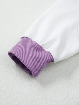 Close-up of a white garment with purple ribbed cuffs on a light gray background