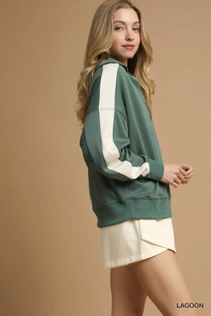Woman wearing a green and white sweatshirt with a beige background